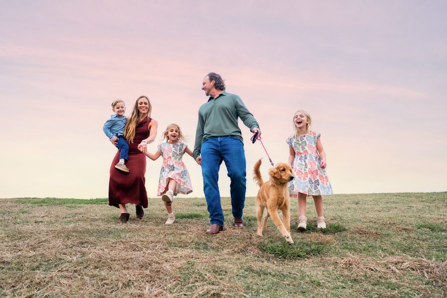 Family walking their dog at sunset