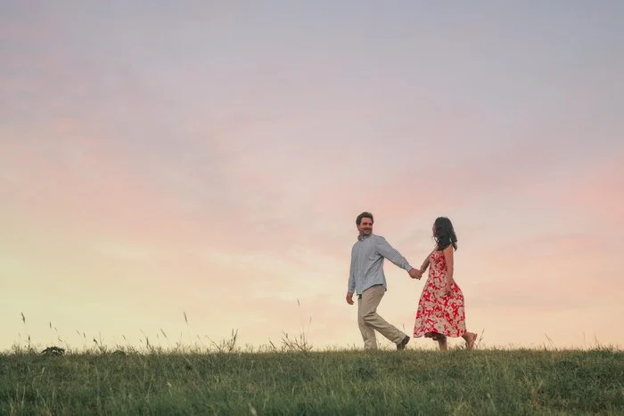 Couple walking a field at sunset